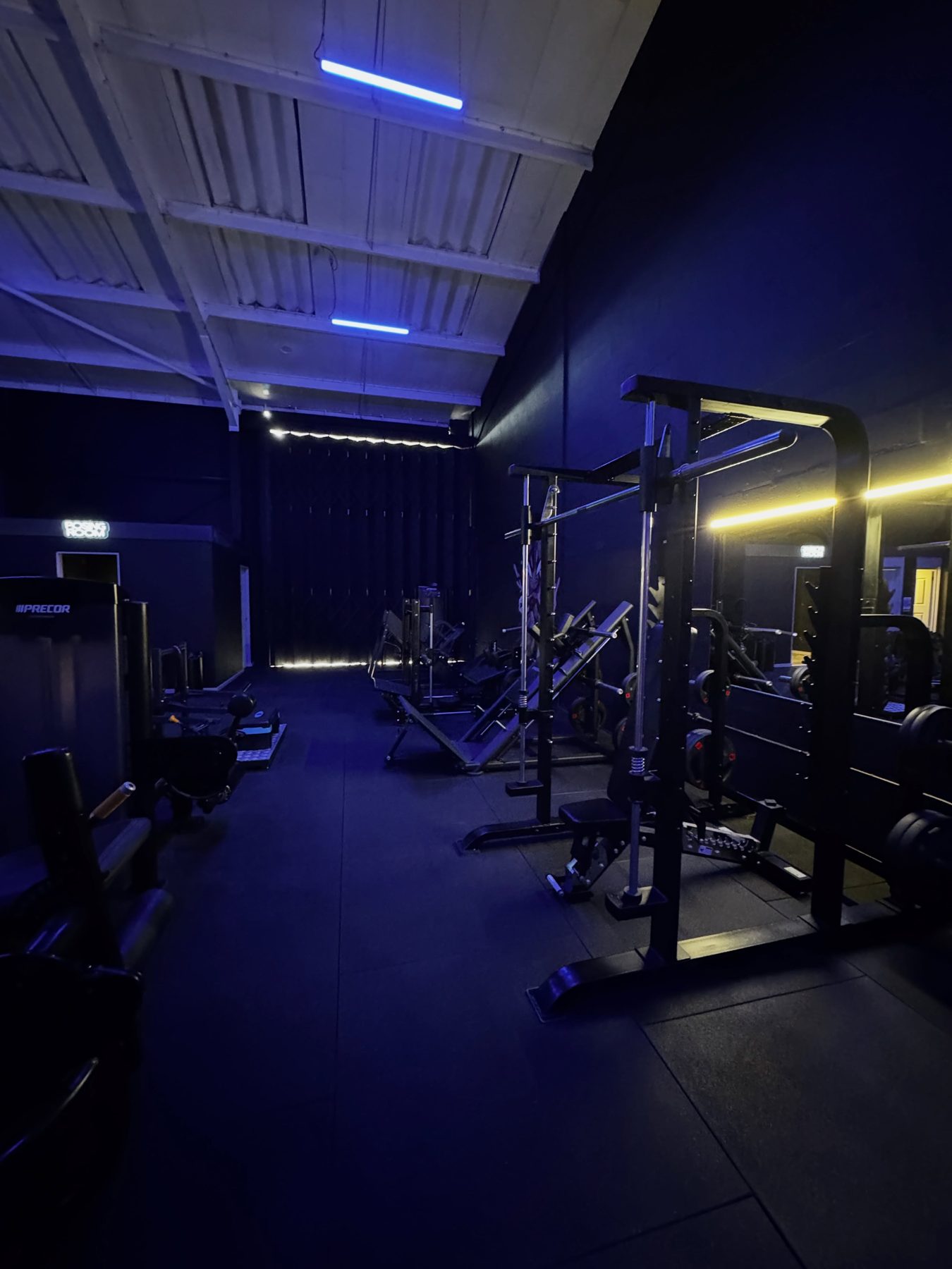 The full gym floor in low light, rows of machines fading into shadow